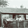 A black & white photo of an old Hampshire cottage, with people standing in front.