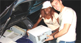Billie Sule and Matthew Baker loading computers into a car boot