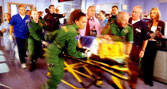 A still from TV show Casualty showing a patient being rushed in on a trolley